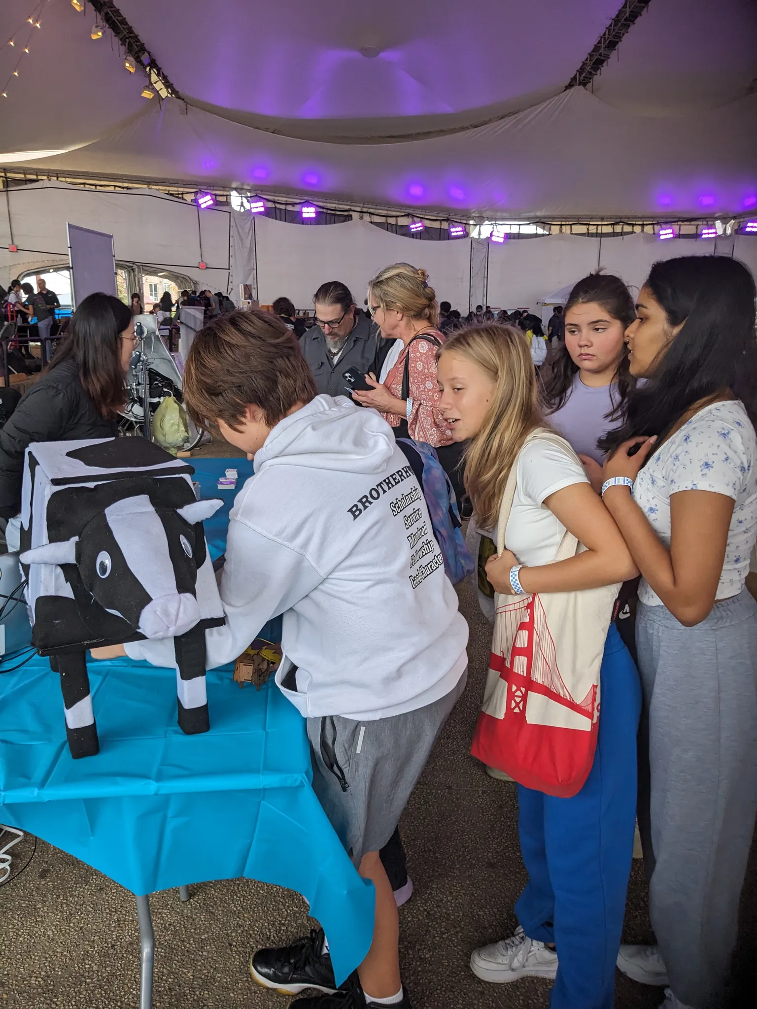 A photograph of a crowd of children gathered around the cow arcade machine.