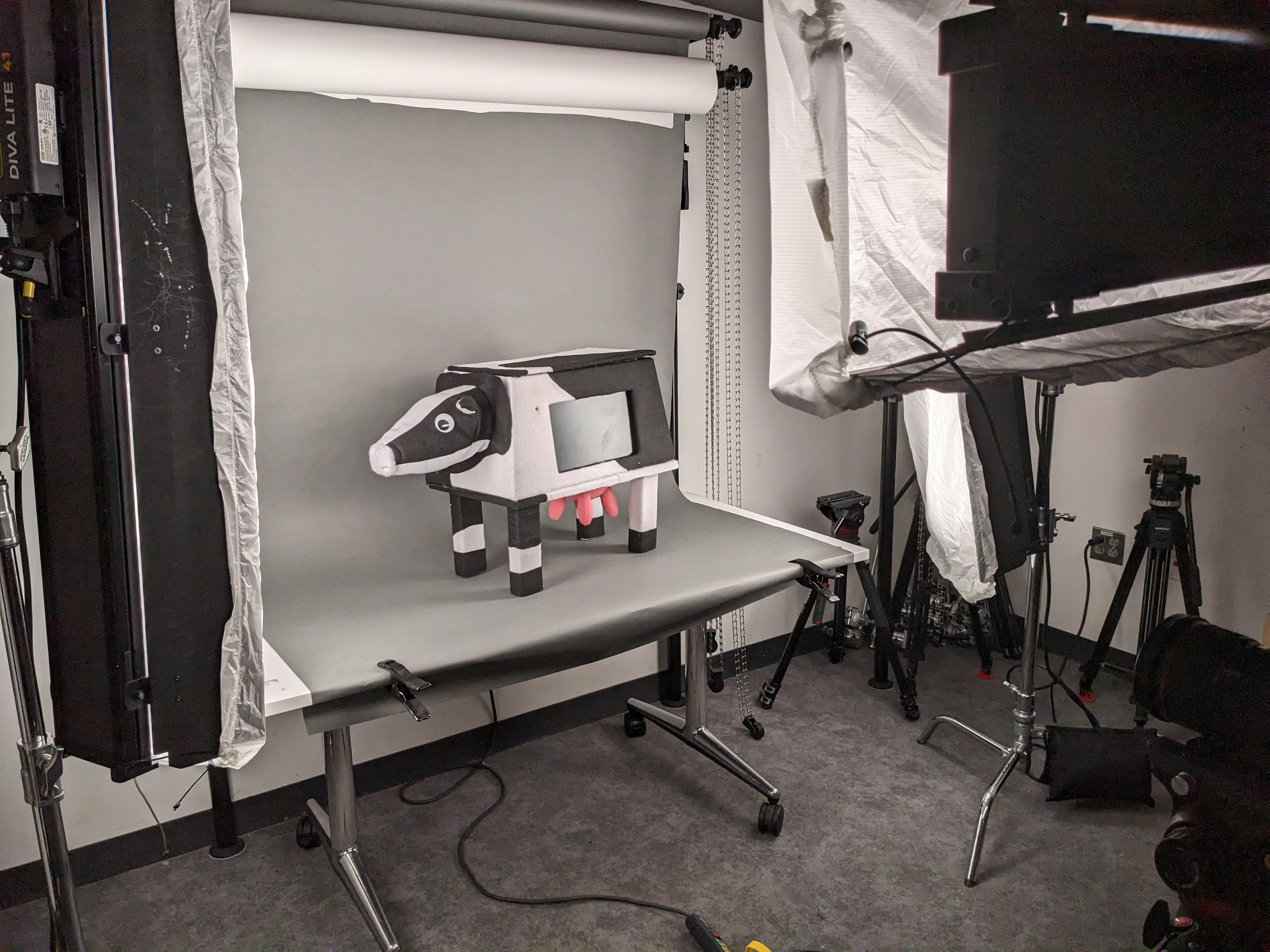 A photograph of a cow video game arcade cabinet on a photography table