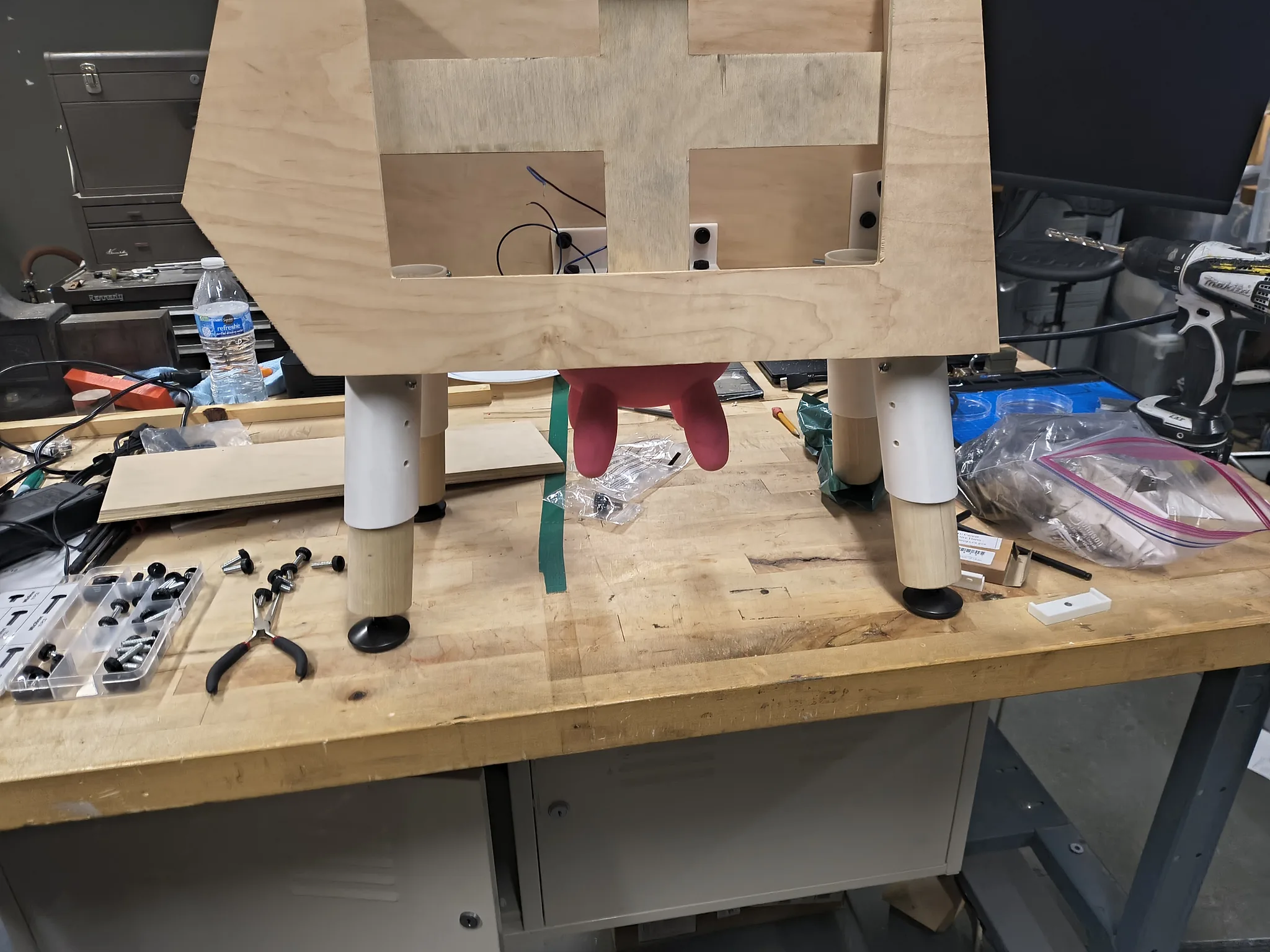Photograph of the plywood cow body assembled on a workbench, udder hanging underneath