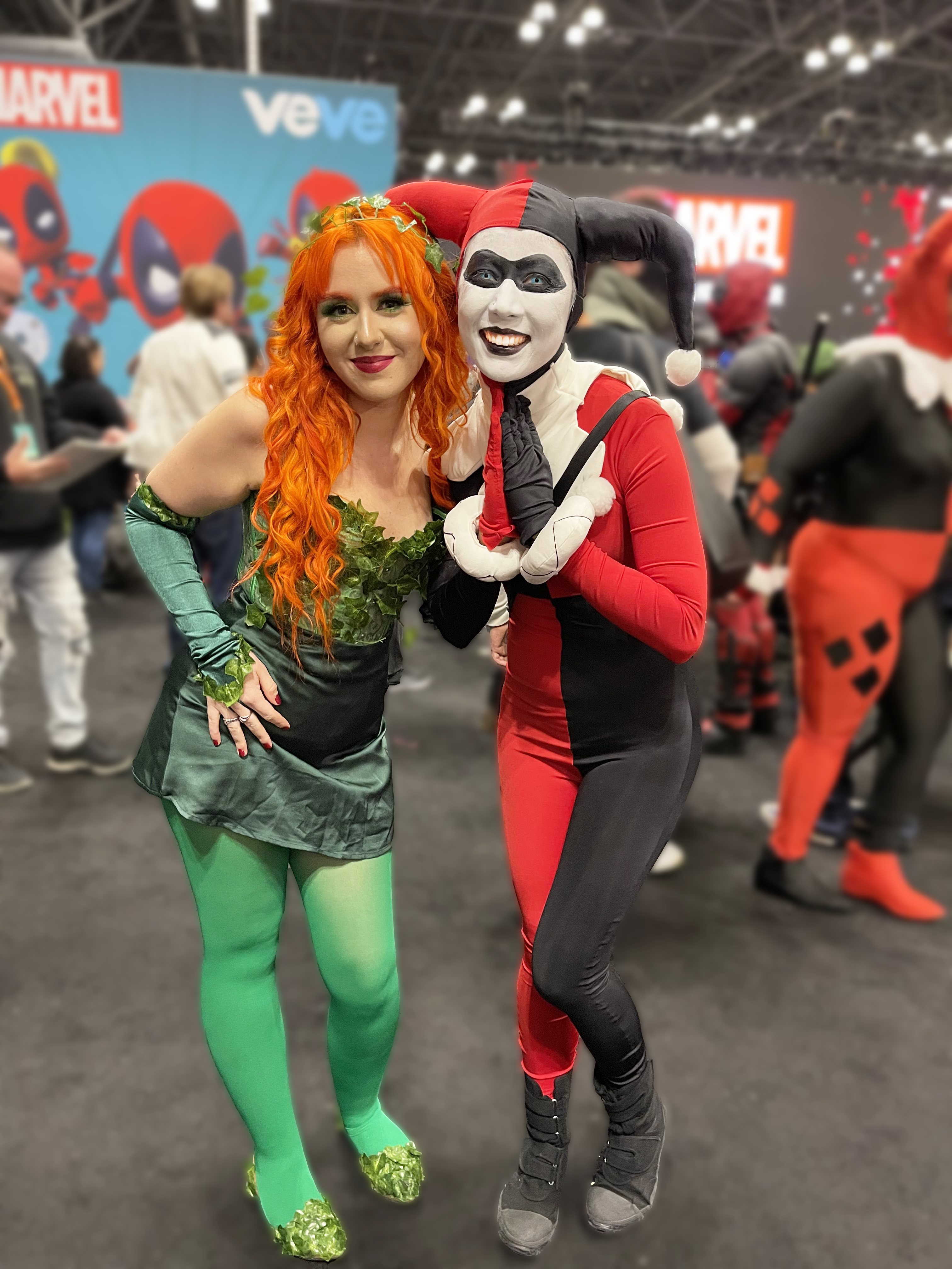 Photograph of a woman in a red and black harlequin outfit next to a girl with red hair and a green leotard