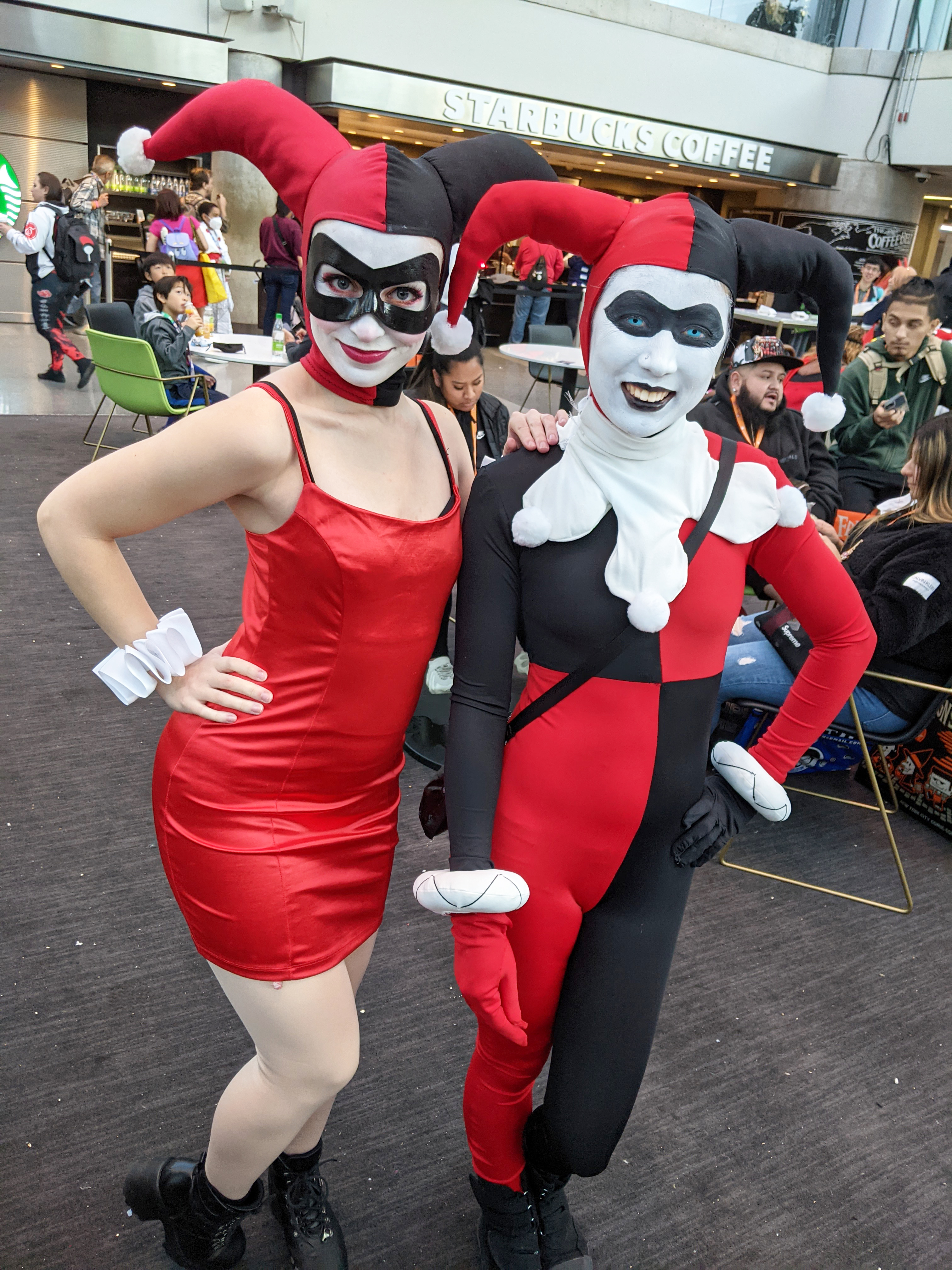 Photograph of a woman in a red and black harlequin outfit standing by another person dressed as the same character but with a red dress