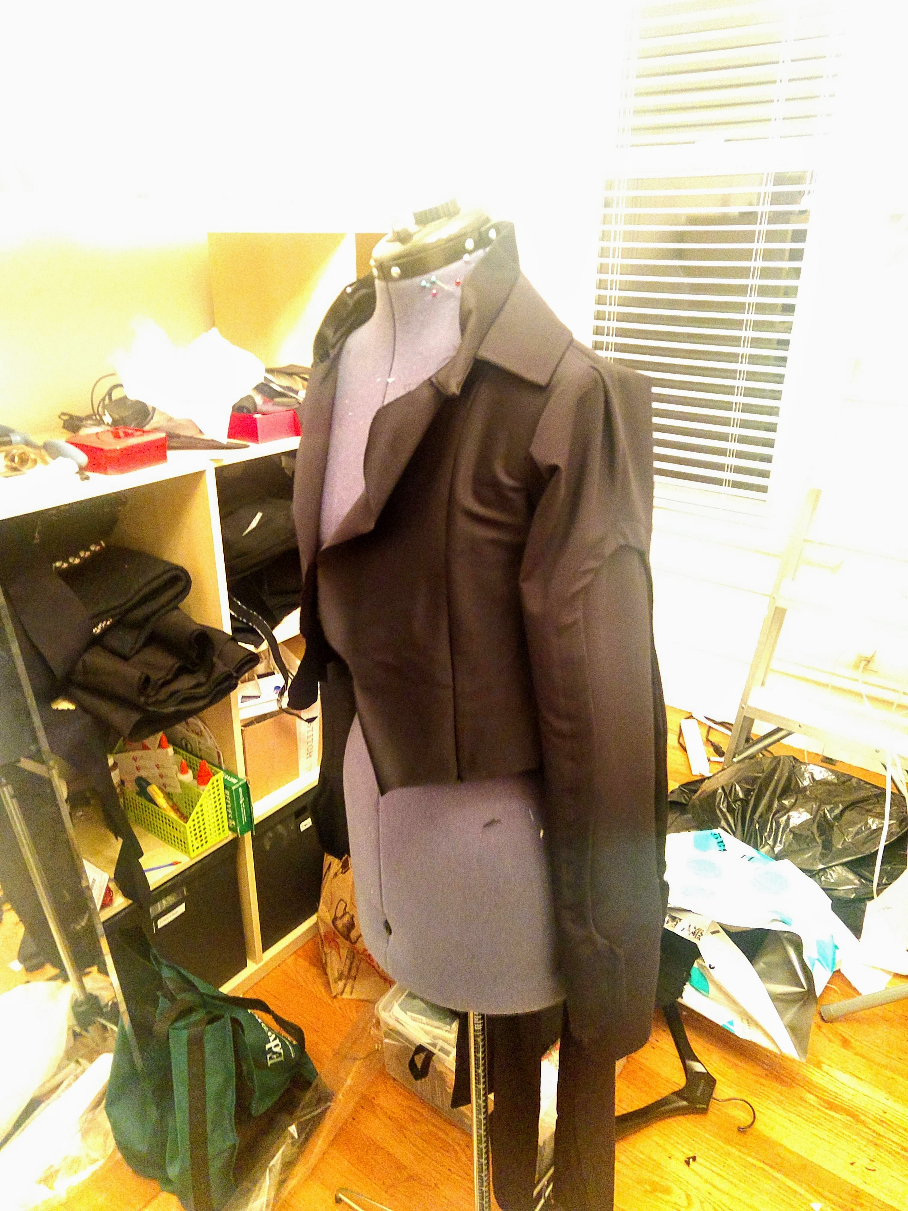 Photograph of a mannequin from the side wearing a black jacket without detailing