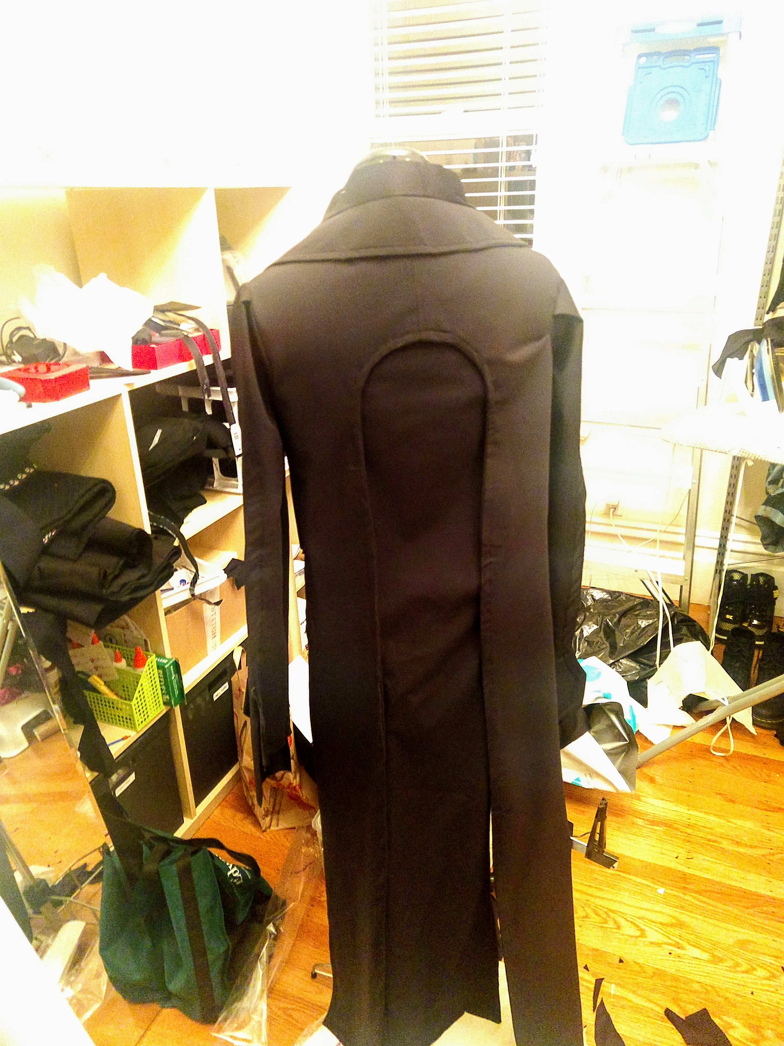 Photograph of a mannequin from the back wearing a black jacket without detailing