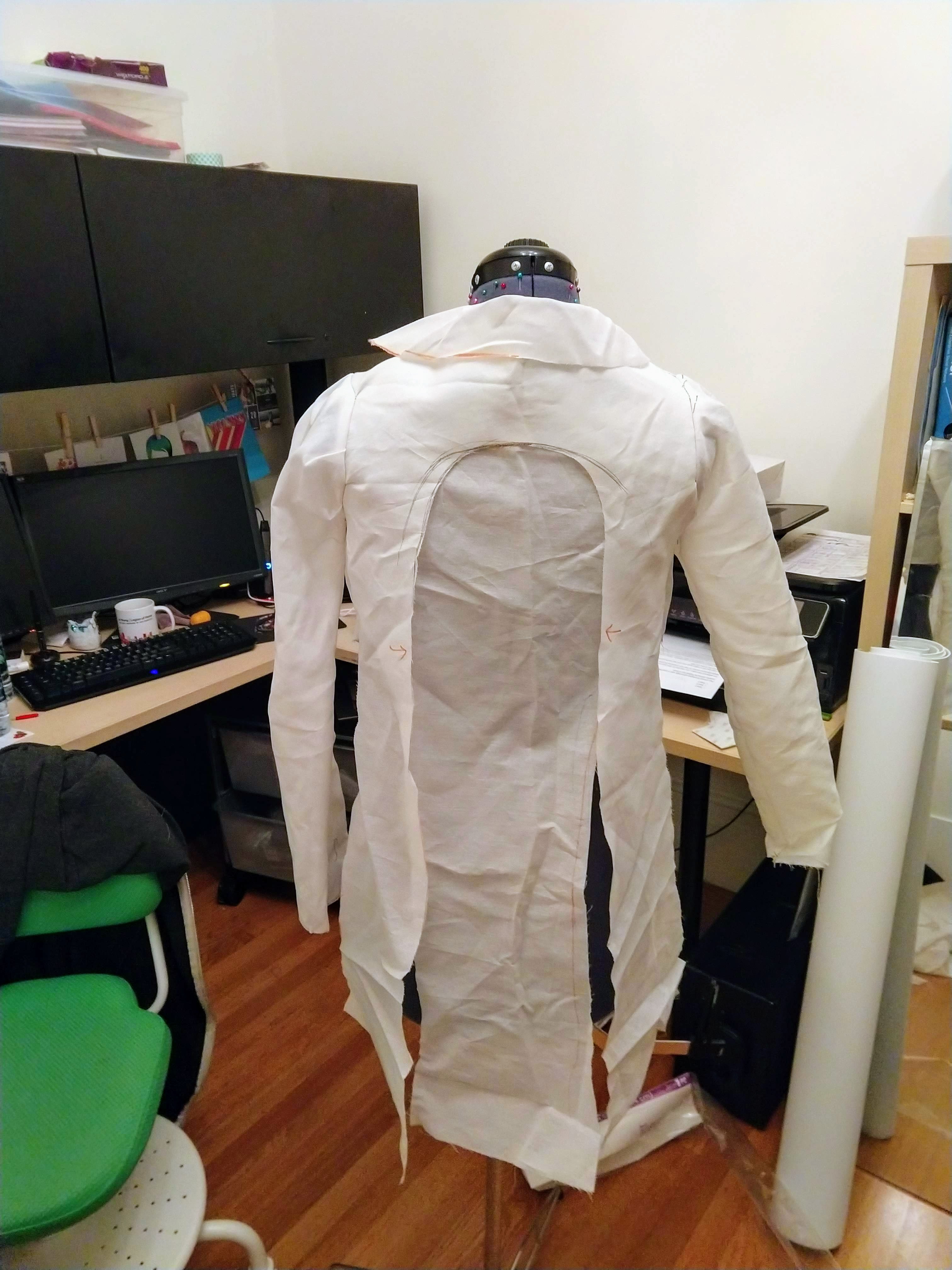 Photograph of a mannequin from the back with white muslin fabric shaped into a jacket with tails