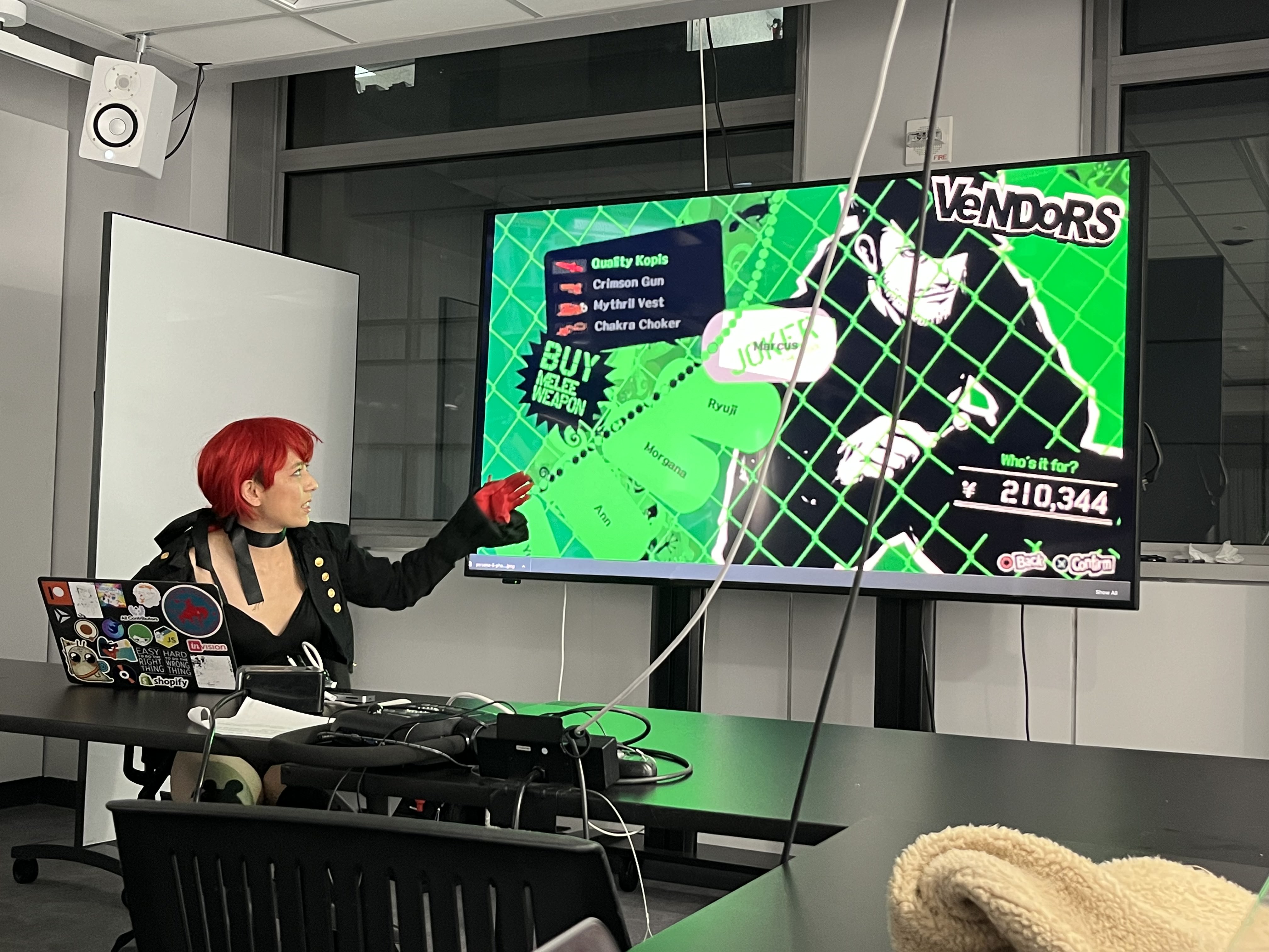 Photograph of a girl in a red wig looking at a screen that says "Vendors"