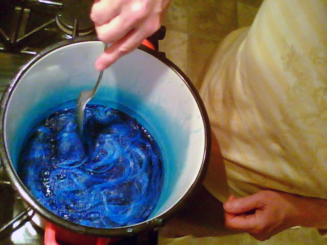 Photograph of a wig in a pot of teal dye. It looks unappetizing