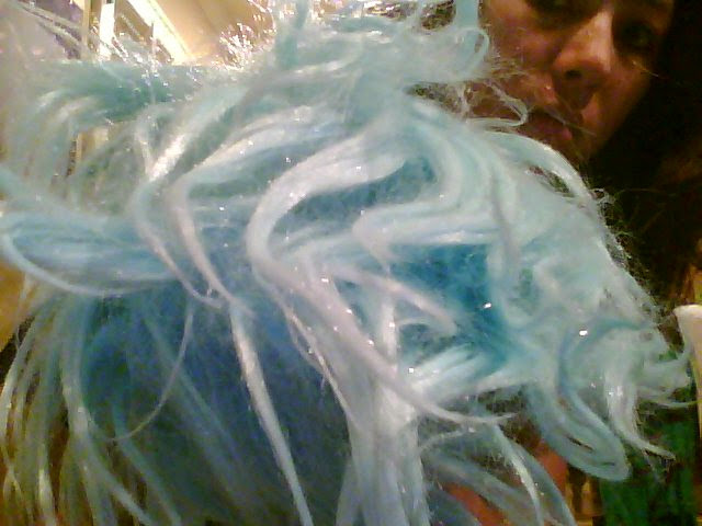 Photograph of a person holding up a very lightly colored blue wig