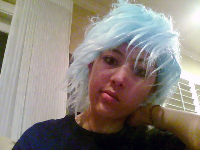 Photograph of a girl wearing a messy light blue wig and looking kind of disappointed