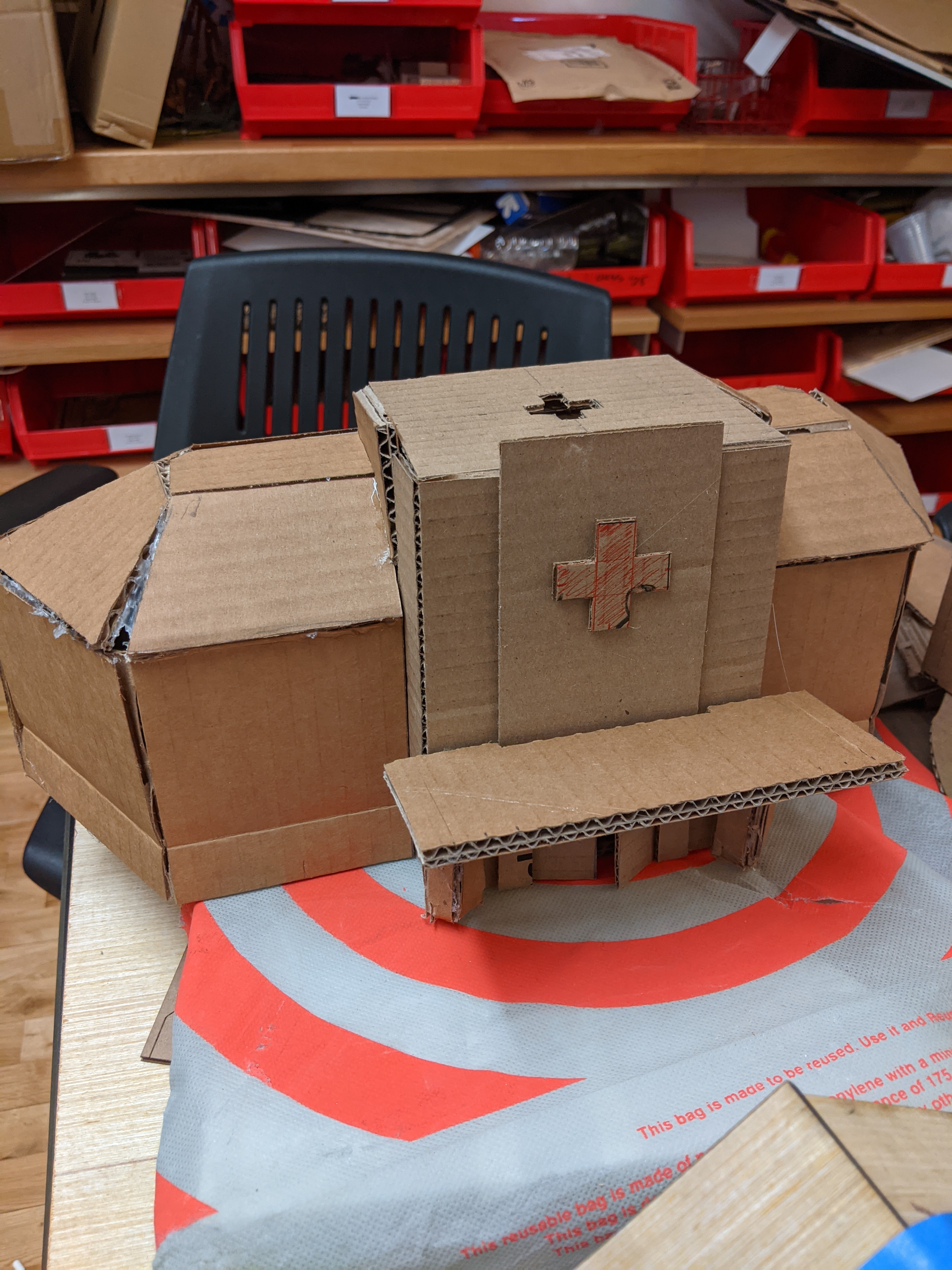 Photograph of a small cardboard building with a cross and a slanted roof