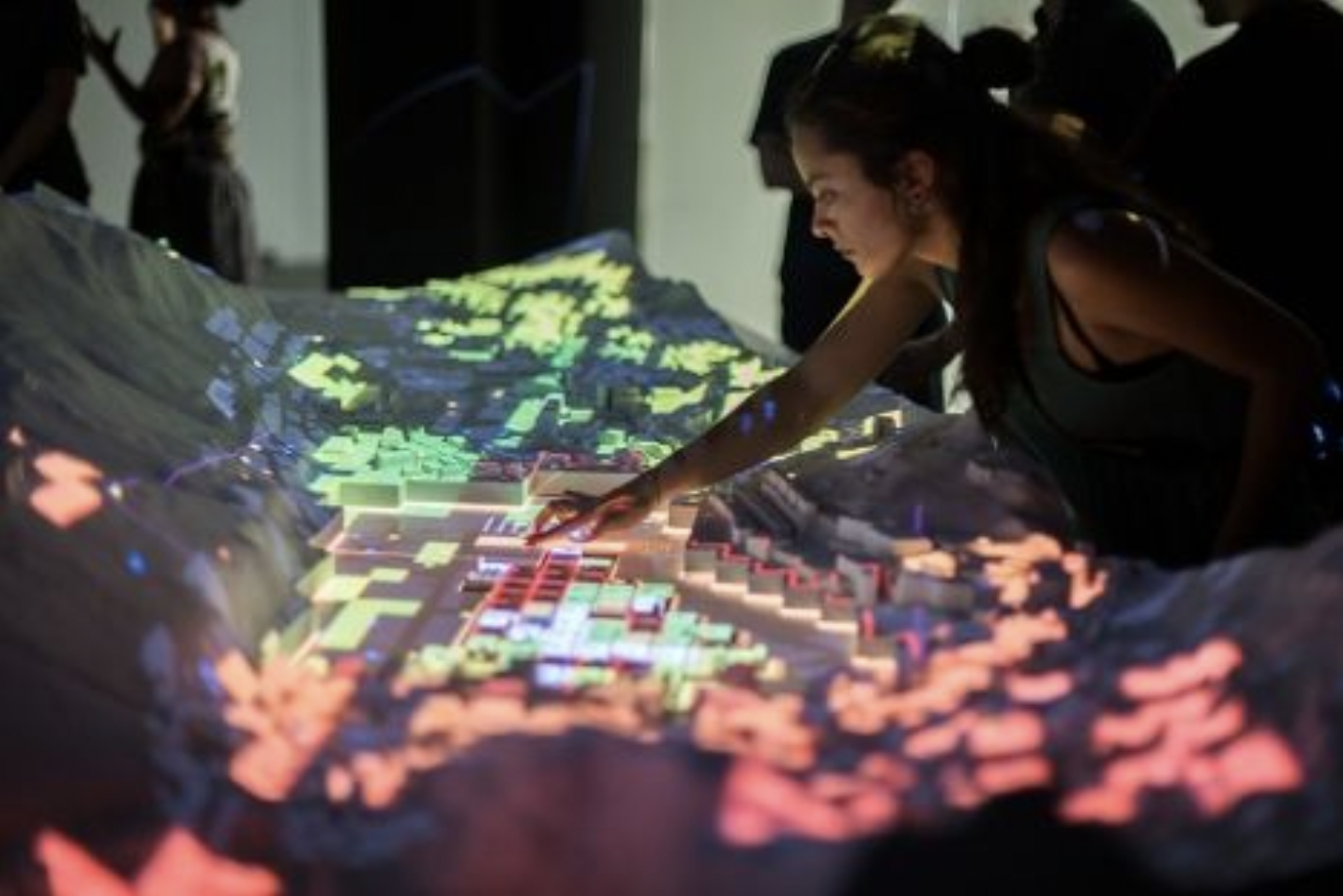 A photograph of people playing with figurines on a table projected with light