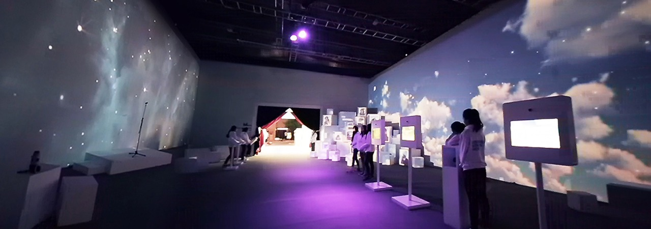 Photograph of a room with kiosks lined up in front of a wall with a sky mural